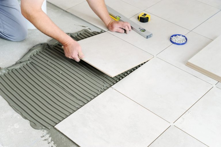 hands-worker-are-laying-ceramic-tile-floor